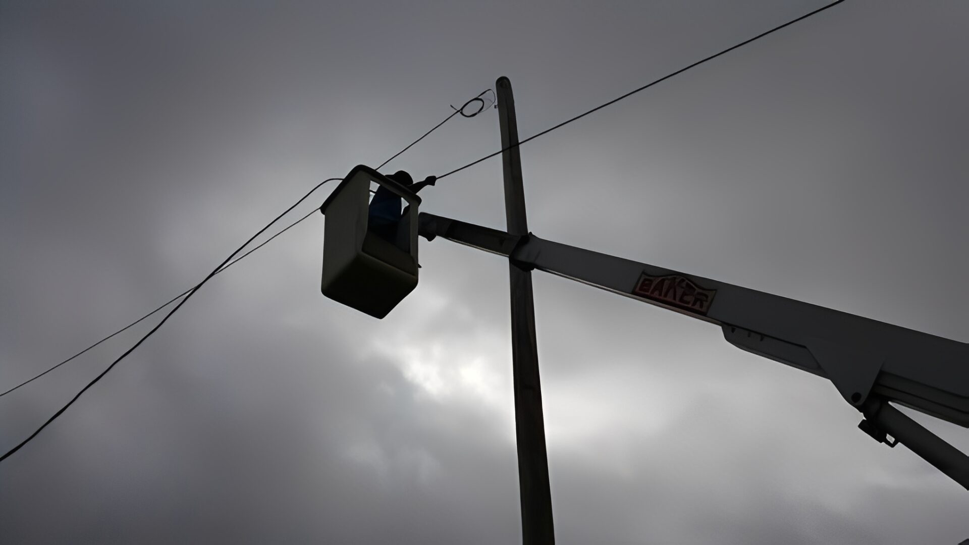 Worker in lift fixing power lines.